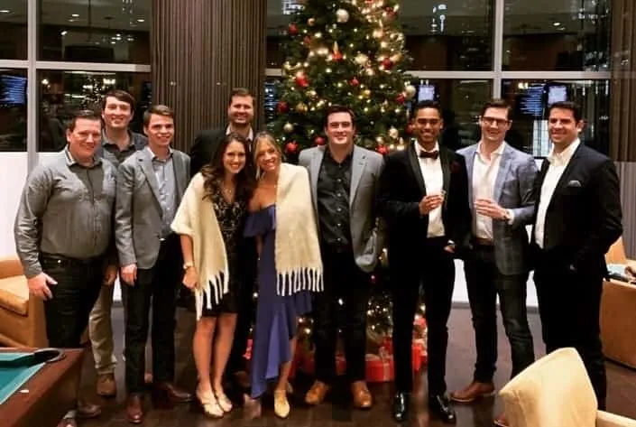 The team dressed up at a holiday party, posed together in front of a decorated Christmas tree